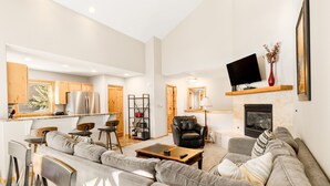 A spacious living area with a sofa set, a coffee table, and a fireplace.