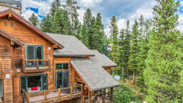 A wooden cabin with a balcony, a staircase, and a satellite dish.