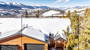 Eine Holzhütte mit verschneitem Dach, einer Garage und einer Terrasse.