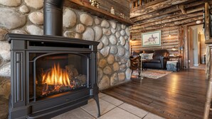 A stone fireplace with a black stove, wooden beams, and a stone wall. - Meet me in the Rockies! Cute cabin 30 min to Breck (Fairplay)