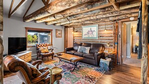 A log cabin interior with a leather sofa, a wooden coffee table, and a large window. - Meet me in the Rockies! Cute cabin 30 min to Breck (Fairplay)