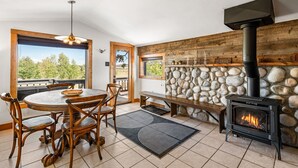 A cozy room with a stone fireplace, a round dining table, and wooden chairs. - Meet me in the Rockies! Cute cabin 30 min to Breck (Fairplay)