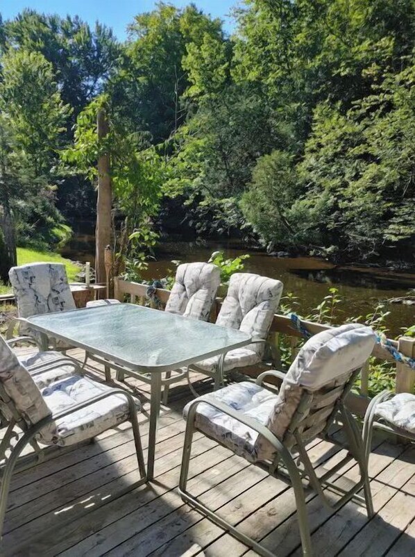 Relax on the deck surrounded by lush greenery and a serene water view.