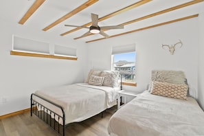 A bedroom with two beds, wooden beams, a ceiling fan, and a window with a view. - Whole House FRONT ROW! No obstructions, just remodeled! (Freeport)