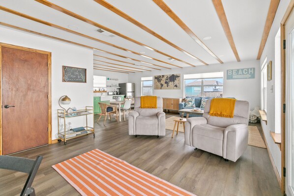 Amplia sala de estar con techo de madera, un conjunto de sofás, una mesita de centro y vistas al exterior.