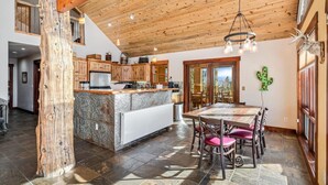 A spacious kitchen with a large island, wooden ceiling beams, and a dining area with a table and chairs.