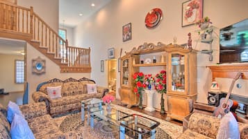 Relax in this stylish living room with a high ceiling, wooden staircase, and comfortable sofas.