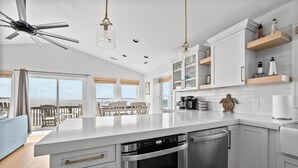 A modern kitchen with white cabinetry, stainless steel appliances, and a large island. - Oceanfront 4BR | Sandcastles + Golden Sunrises (Surf City)