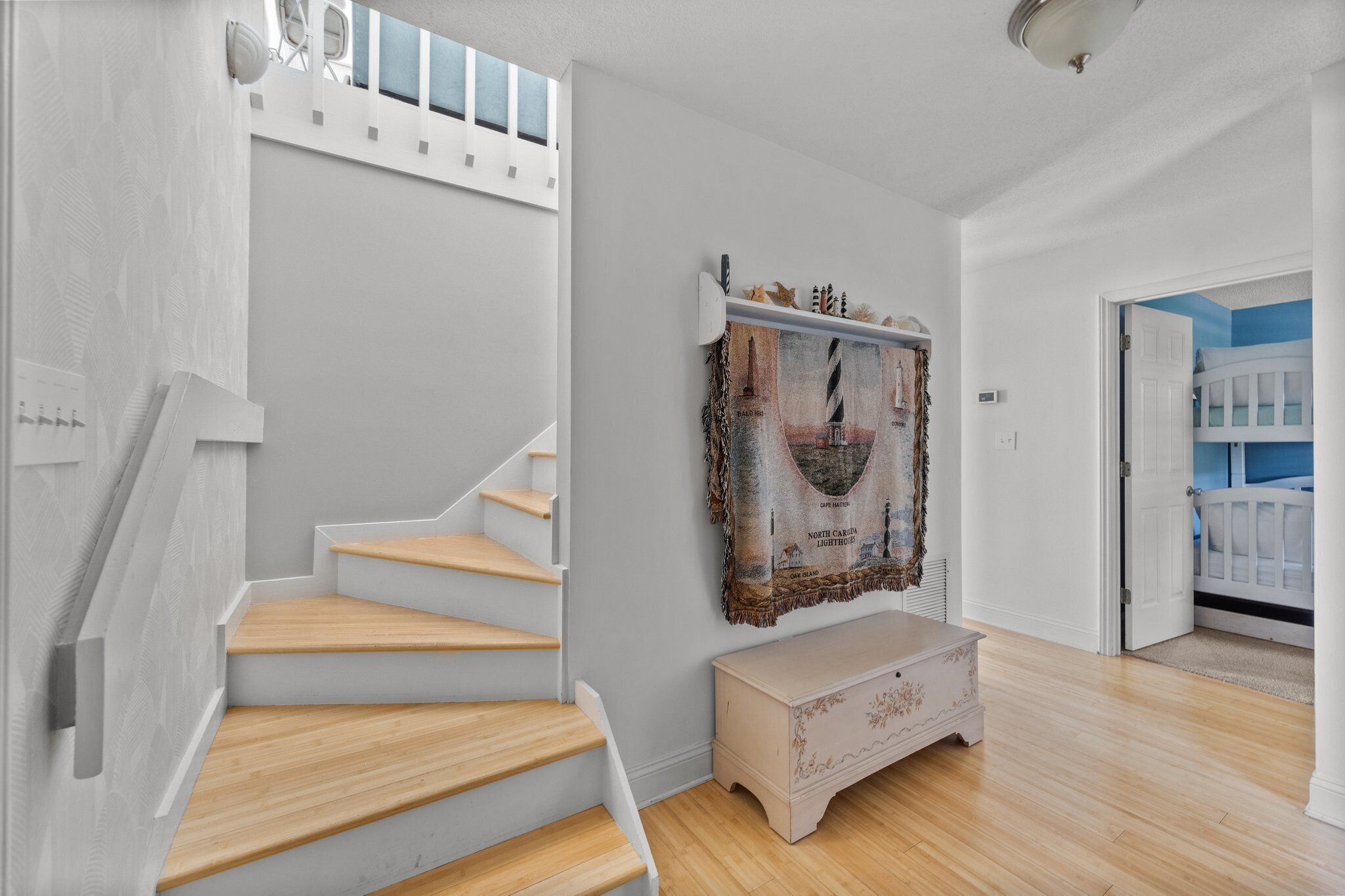 A staircase with wooden steps and white walls, a bench, and a wall-mounted picture frame.