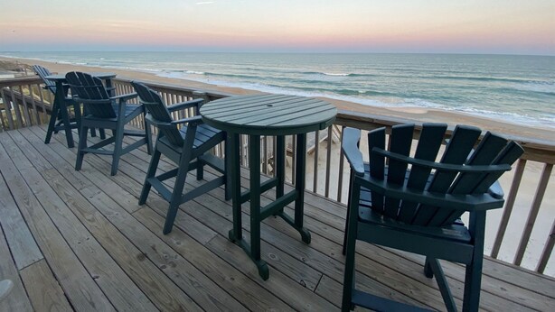 A wooden deck with chairs and a table overlooking the ocean. - Twin Landings | Two Homes, One Epic Family Escape! (Surf City)