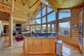 A spacious kitchen with large windows, wooden cabinets, and a central island.