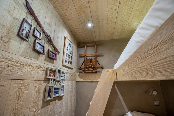 A room with wooden walls, a slanted ceiling, and a bed with a wooden headboard. - Grangettes 1 ski-in & ski-out (Les Allues)