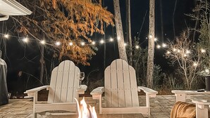 An outdoor seating area with Adirondack chairs, a fire pit, and string lights. - 30a Calm Gulf Cottage -1 mile from beach + golf cart (Santa Rosa Beach)