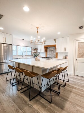 A modern kitchen with a large island, stainless steel appliances, and a chandelier. - 30a Calm Gulf Cottage -1 mile from beach + golf cart (Santa Rosa Beach)