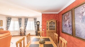 A dining area with a wooden table and chairs, a clock, and a cabinet with glass doors. - Casa La Mirada - RCP152 Cómpeta by Ruralidays (Málaga)