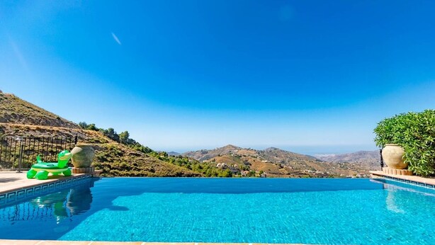 A clear blue pool with a green inflatable toy, a large pot, and a potted plant on the right side. - Casa La Mirada - RCP152 Cómpeta by Ruralidays (Málaga)