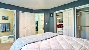 Un dormitorio con cama, armario y baño visible a través de una puerta abierta.