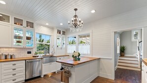 A spacious kitchen with white cabinetry, a wooden island, and a chandelier. - 1910 Farmhouse: Chef’s Kitchen + Fire Pit + Studio - Near Wedding & Wine Country (Wilsonville)