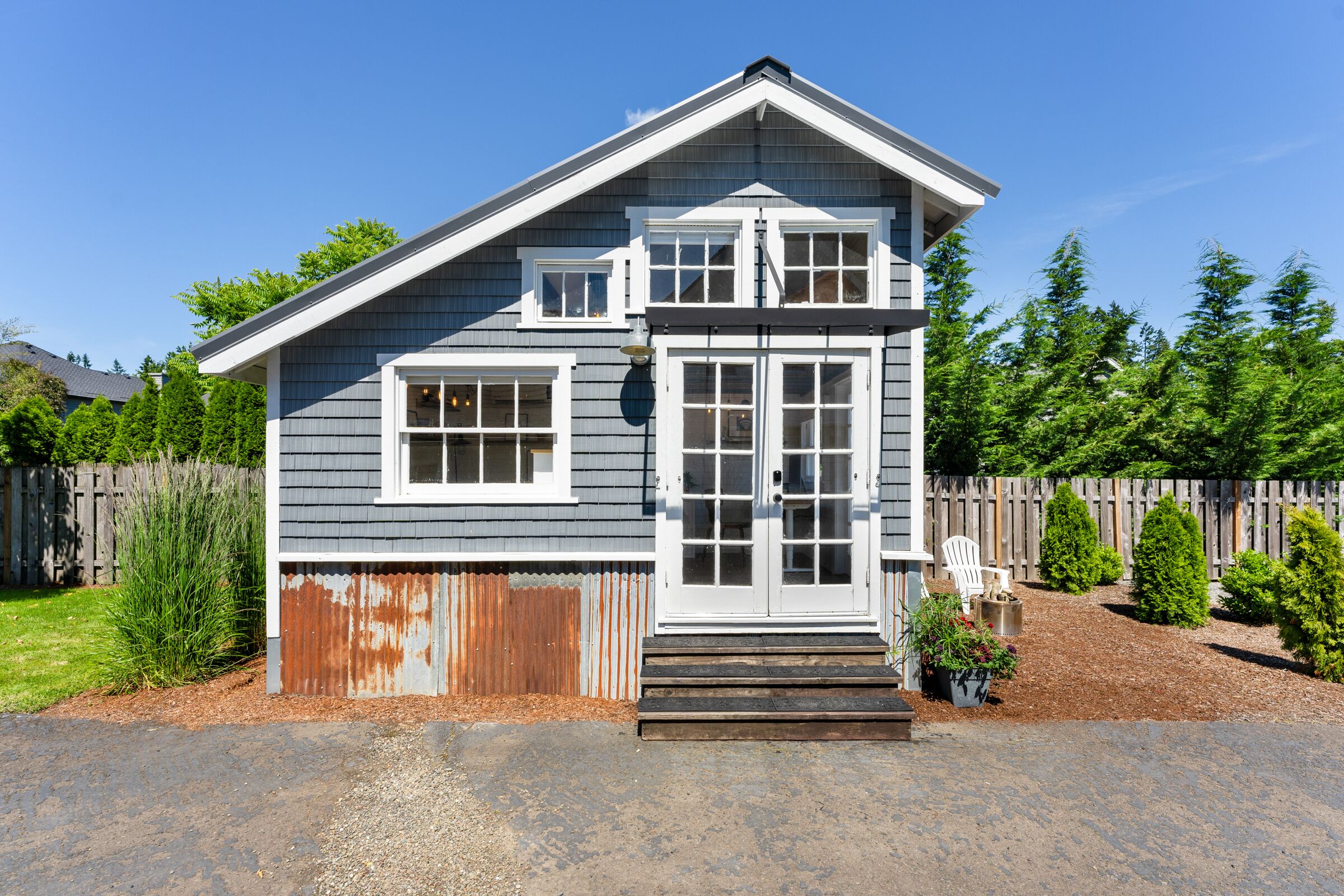 A two-story house with a front porch, a wooden fence, and a well-maintained garden.