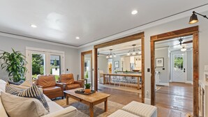 Un salón amplio con un sofá grande, una mesa de centro y un comedor con una cocina al fondo.