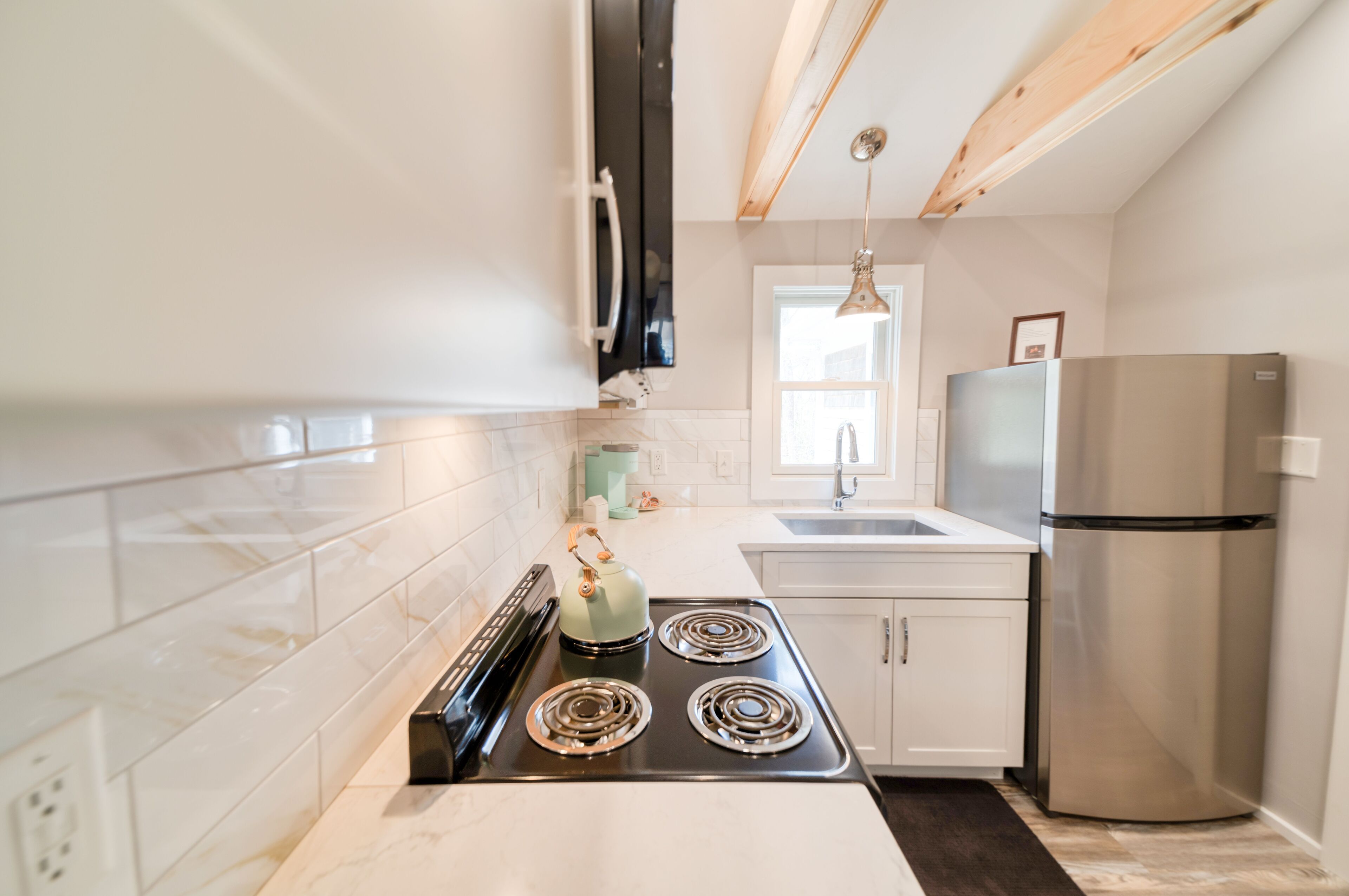 A modern kitchen with white cabinets, a stainless steel refrigerator, and a gas stove.