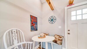 Ein gemütliches Zimmer mit weißem Sessel, einem kleinen Rundtisch, einer Wanddekoration und einer Tür mit einem Notausgangsschild.