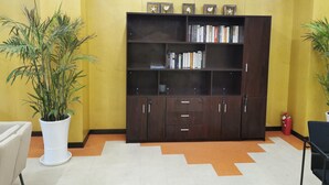 A room with a wooden bookshelf, a potted plant, and a fire extinguisher.