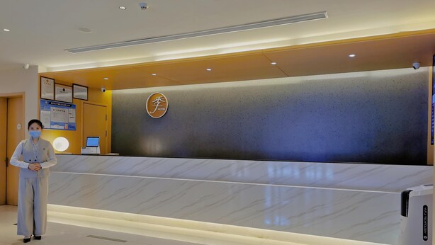 A hotel reception desk with a modern design, a digital screen, and a security camera.