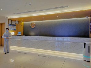 A hotel reception desk with a modern design, a digital screen, and a security camera. - Ji Hotel (Nanjing)