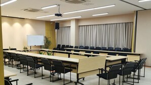 A conference room with a long table, chairs, a whiteboard, and a projector.