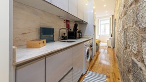 Una cocina moderna con lavadora integrada, microondas y hervidor.