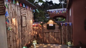 A wooden gate with flags, a concrete pathway, and potted plants. - Mesmerize Guest House (Port Antonio)