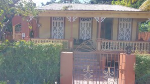 A house with a gated entrance, a tiled roof, and decorative window grills. - Mesmerize Guest House (Port Antonio)