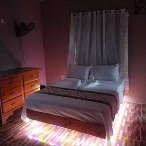 Une chambre à coucher avec un lit, une commode en bois et un luminaire fixé au mur.