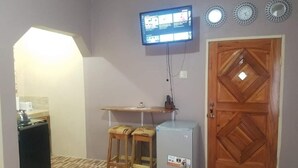 A compact kitchen with a built-in oven, a small refrigerator, and a wooden door. - Mesmerize Guest House (Port Antonio)