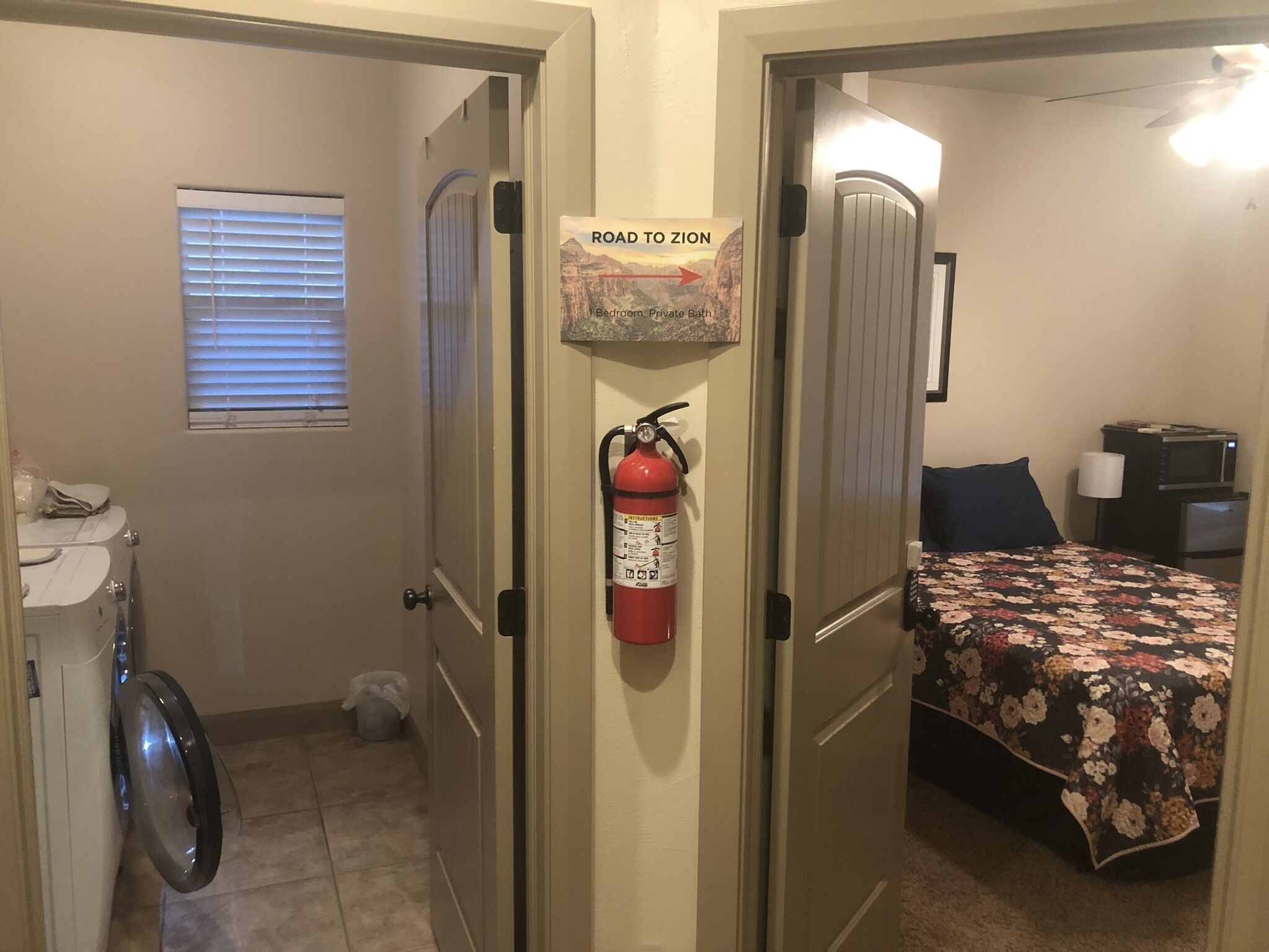 Un dormitorio con una cama, un extintor y una puerta con un cartel que dice 'Road to Zion'.