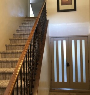 Staircase leads to a landing with a door featuring vertical slats and a framed picture on the wall.