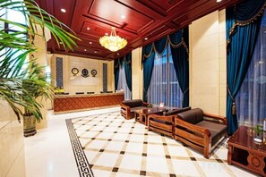 A lobby with a checkered floor, a reception desk, seating area with sofas and a coffee table, and a large chandelier. - Xinwei Business Hotel (Suihua)