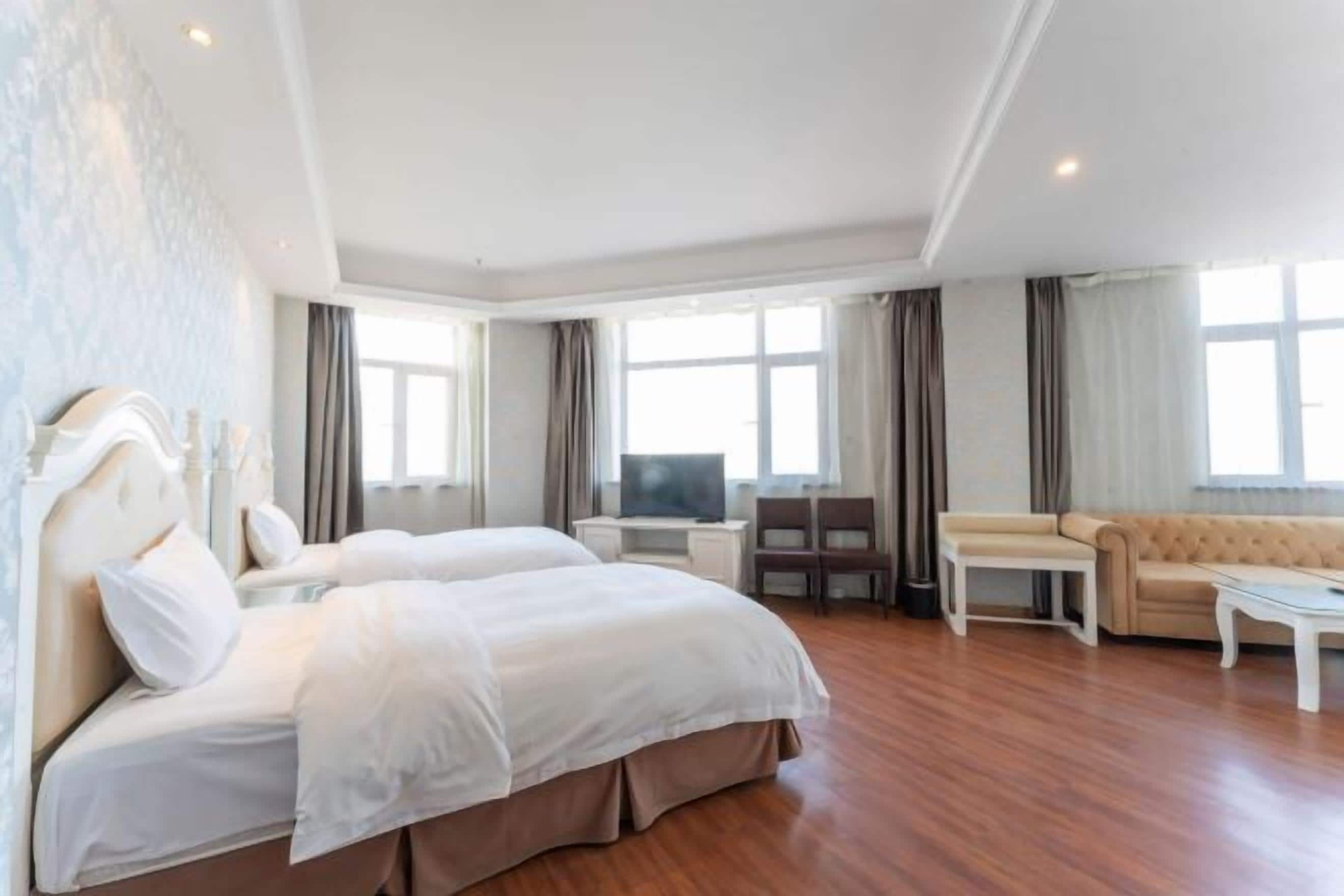 A hotel room with a large bed, a sofa, a TV, and a desk.