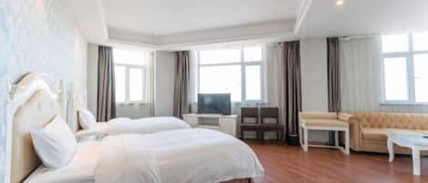 A hotel room with a large bed, a sofa, a TV, and a desk.