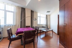 Ein Hotelzimmer mit Bett, Schreibtisch, Sessel, Sofa, Lampe und Kleiderschrank.