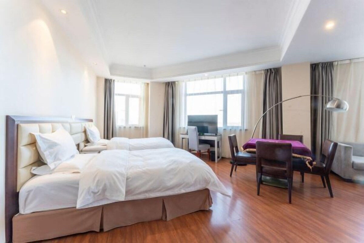 Ein Hotelzimmer mit einem großen Bett, einem Schreibtisch, einem Sessel und einem Fernseher.
