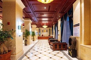Um saguão de hotel com balcão de recepção, área de estar e piso estampado.