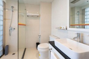 Ein modernes Badezimmer mit einer Duschkabine, einer weißen Toilette und einem großen Waschbecken mit schwarzer Arbeitsplatte.
