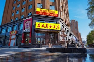 Un hotel con un llamativo letrero amarillo, una fuente en primer plano y un edificio alto al fondo.