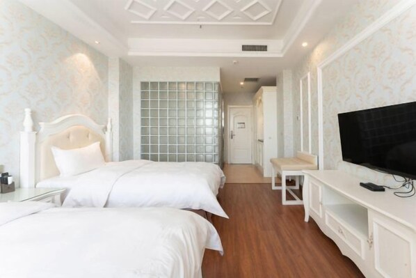 Ein Hotelzimmer mit zwei Betten, einem Fernseher, einem kleinen Tisch und einem Kleiderschrank.