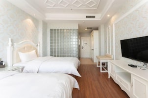 Habitación de hotel con dos camas, televisión, una mesita y un armario.