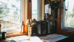 A kitchen with a microwave, a plant, and utensils on the counter. - It is a tiny home in the treehouse located in the middle of Fairbanks. (Fairbanks)