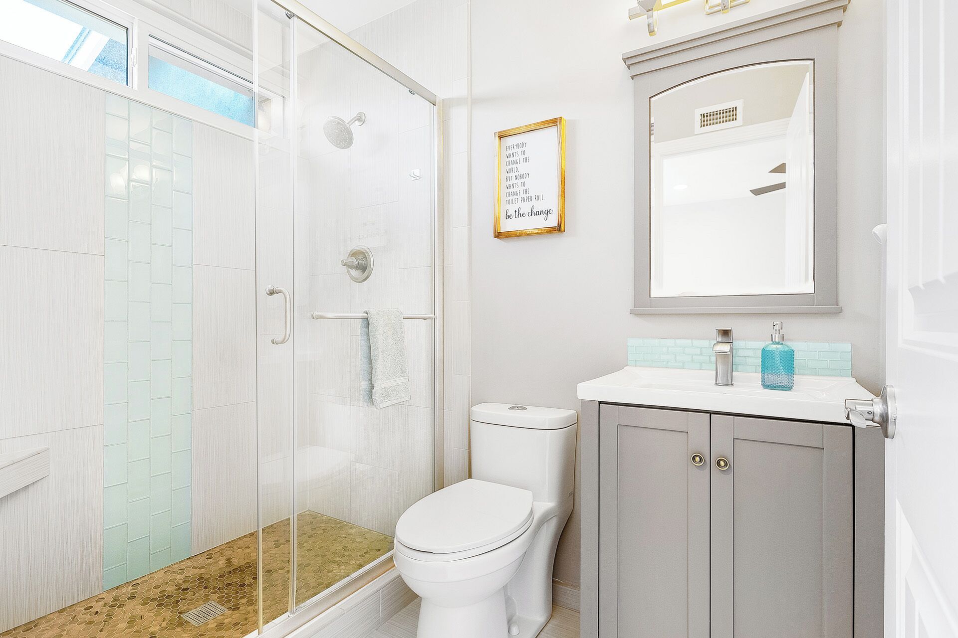 Un bagno moderno con box doccia in vetro, un water e un mobile lavabo con specchio.