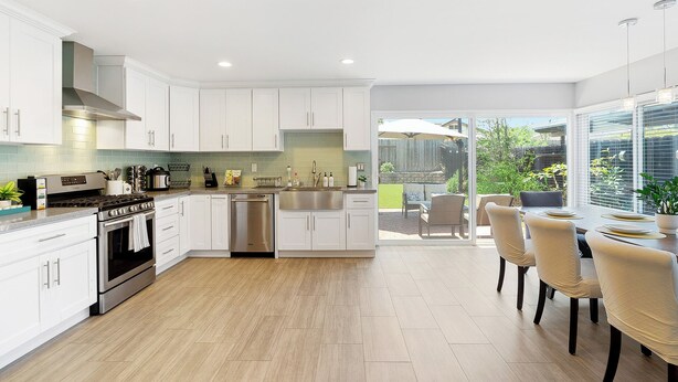 Una cucina moderna con mobili bianchi, elettrodomestici in acciaio inossidabile e un'isola grande.